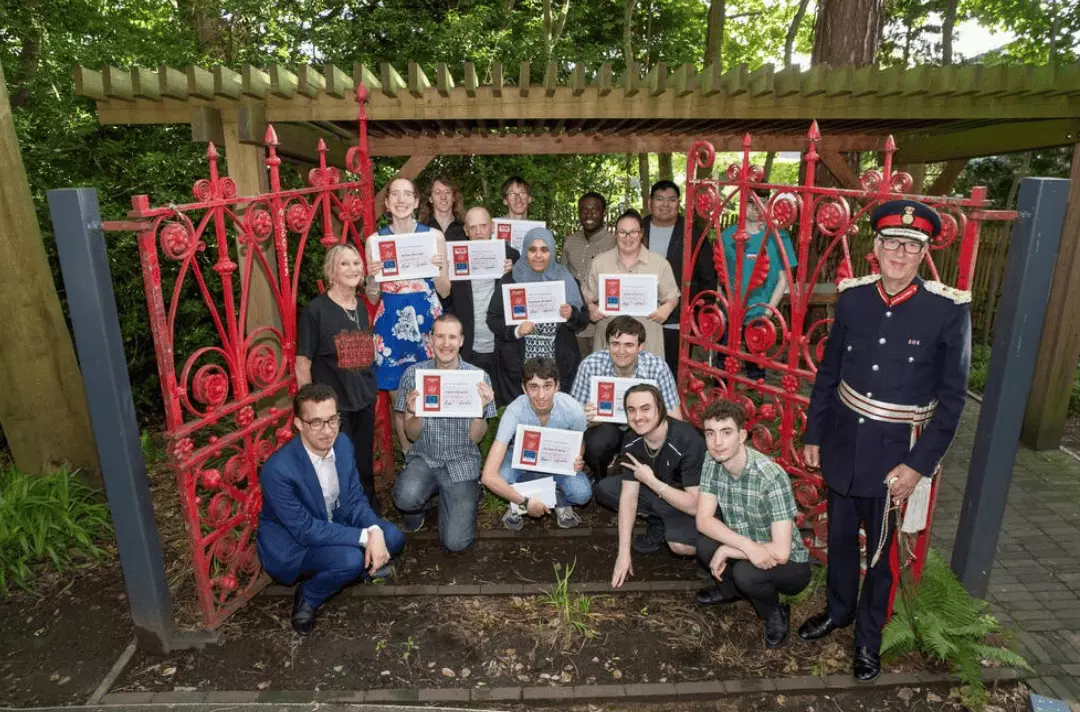 Graduates from Steps at Strawberry Field programmes celebrate at the iconic red gates