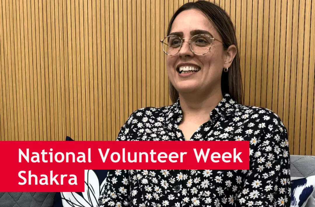 Shakra, a volunteer at Strawberry Field, sat on a sofa with a big smile. There is text overlay which reads 'National Volunteer Week, Shakra'