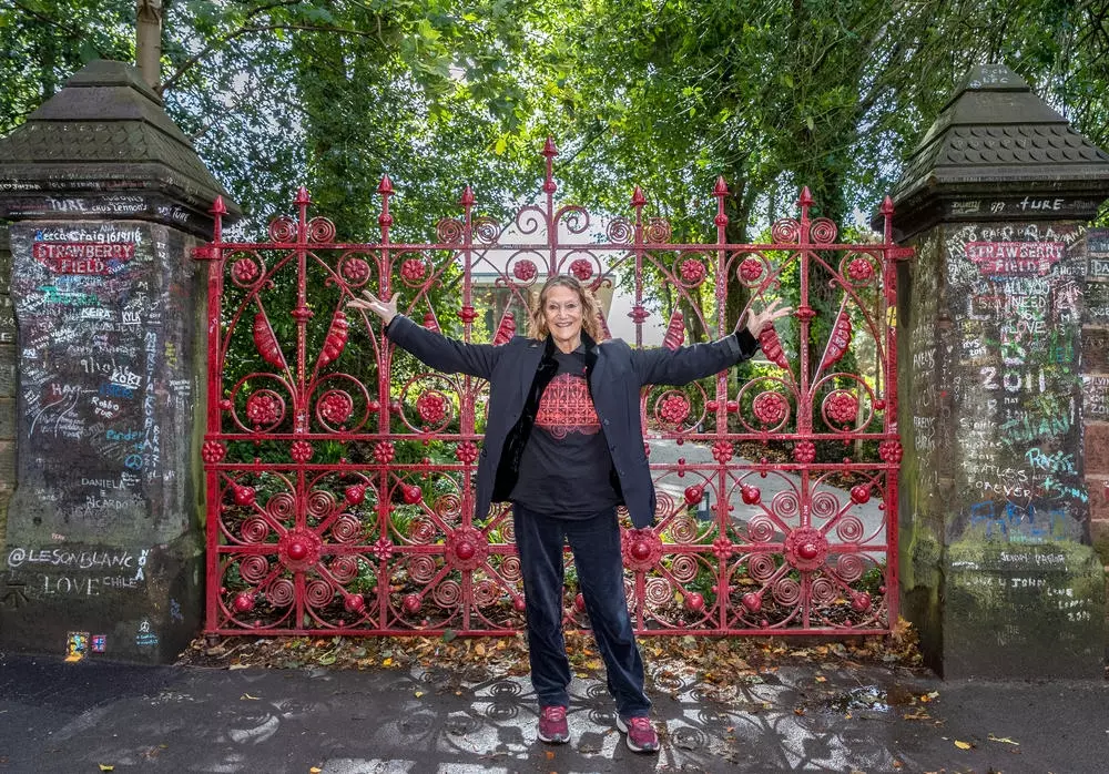 Julia Baird standing in front of the red Strawberry Field gates.