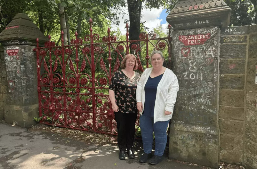 Karen and Liz stand outside the Strawberry Field gates