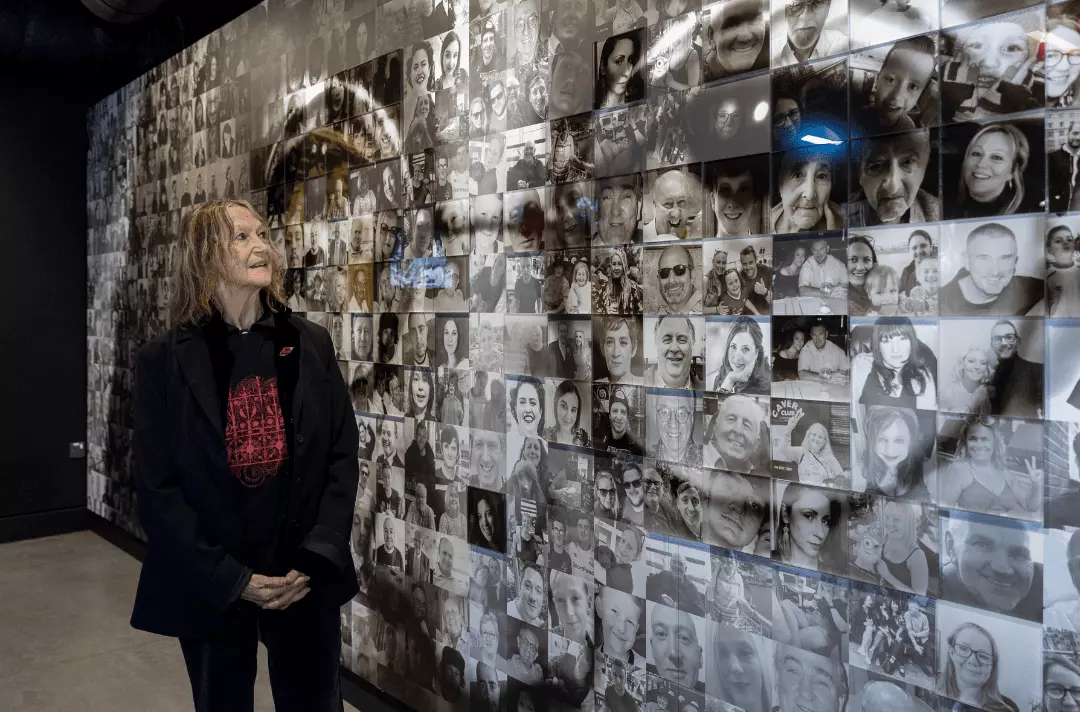 Julia Baird stands and looks up at the John Lennon photomosaic