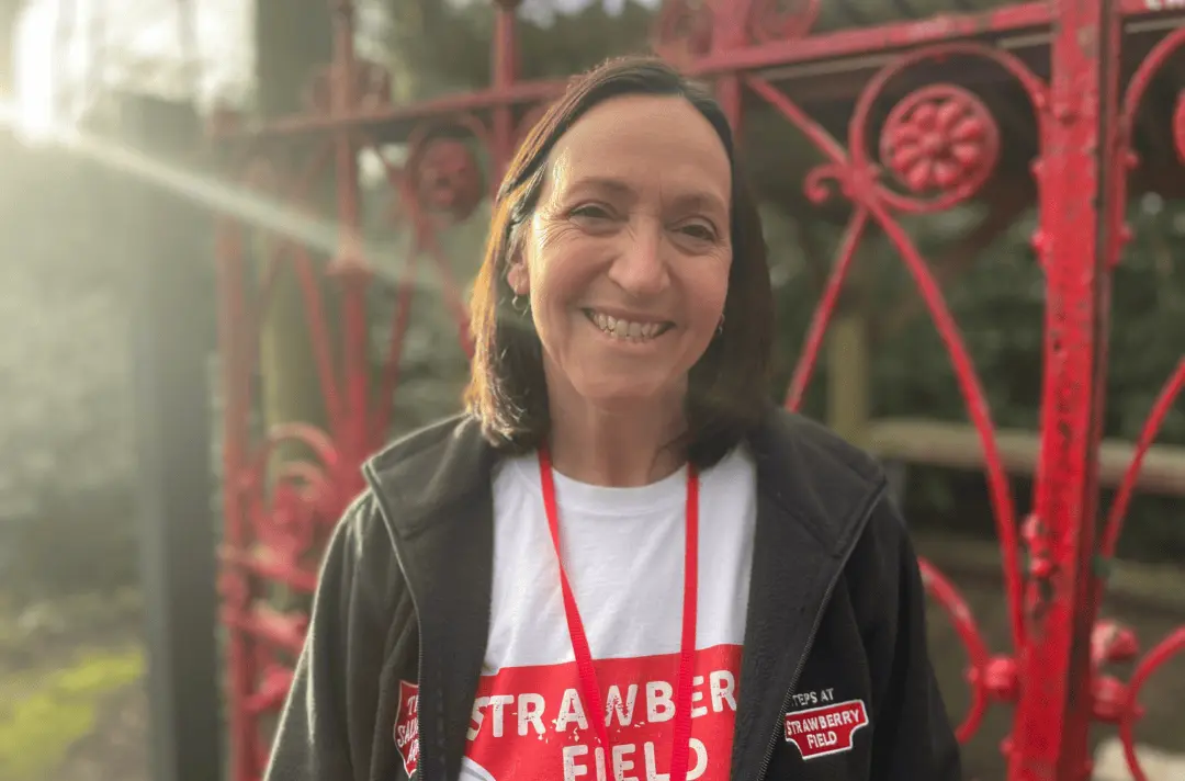 A woman with shoulder length brown hair wearing a white tshirt that says ;Strawberry Field.