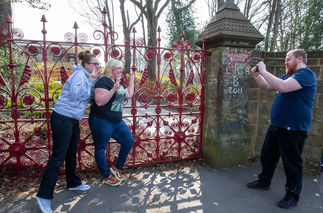 Two women having their photo taken at the red Strawberry Field gates.