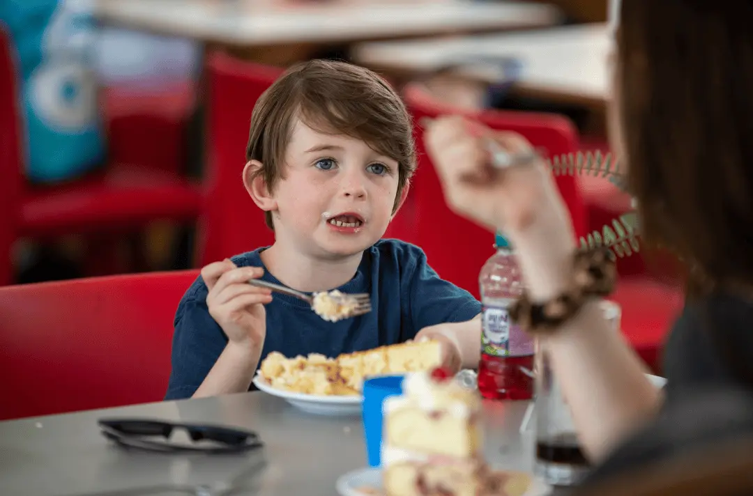 A little boy eating cake in the Imagine More cafe at Strawberry Field