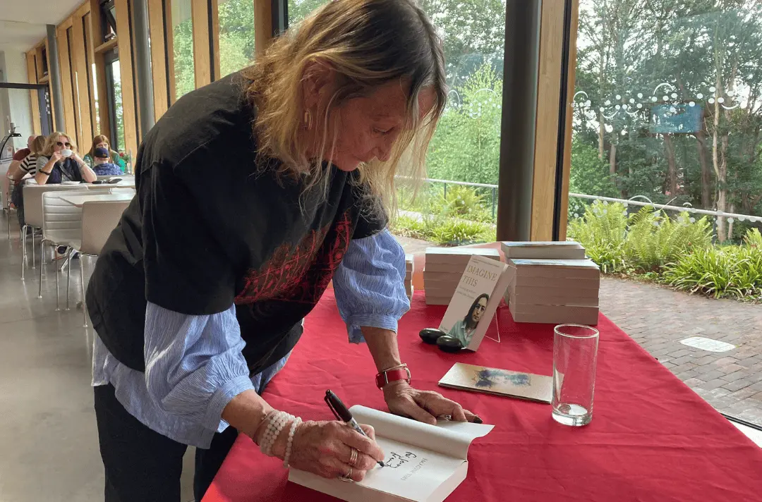 Julia Baird leans over and signs a copy of her book 'Imagine This'.