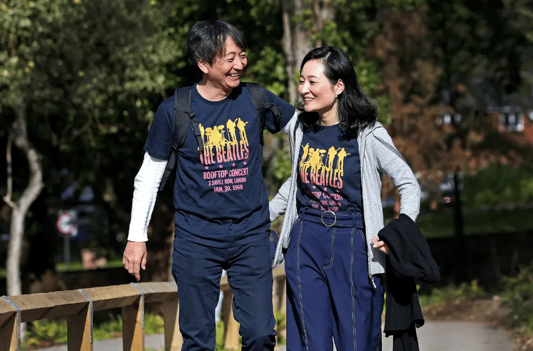 A couple walk through the Strawberry Field garden smiling and laughing