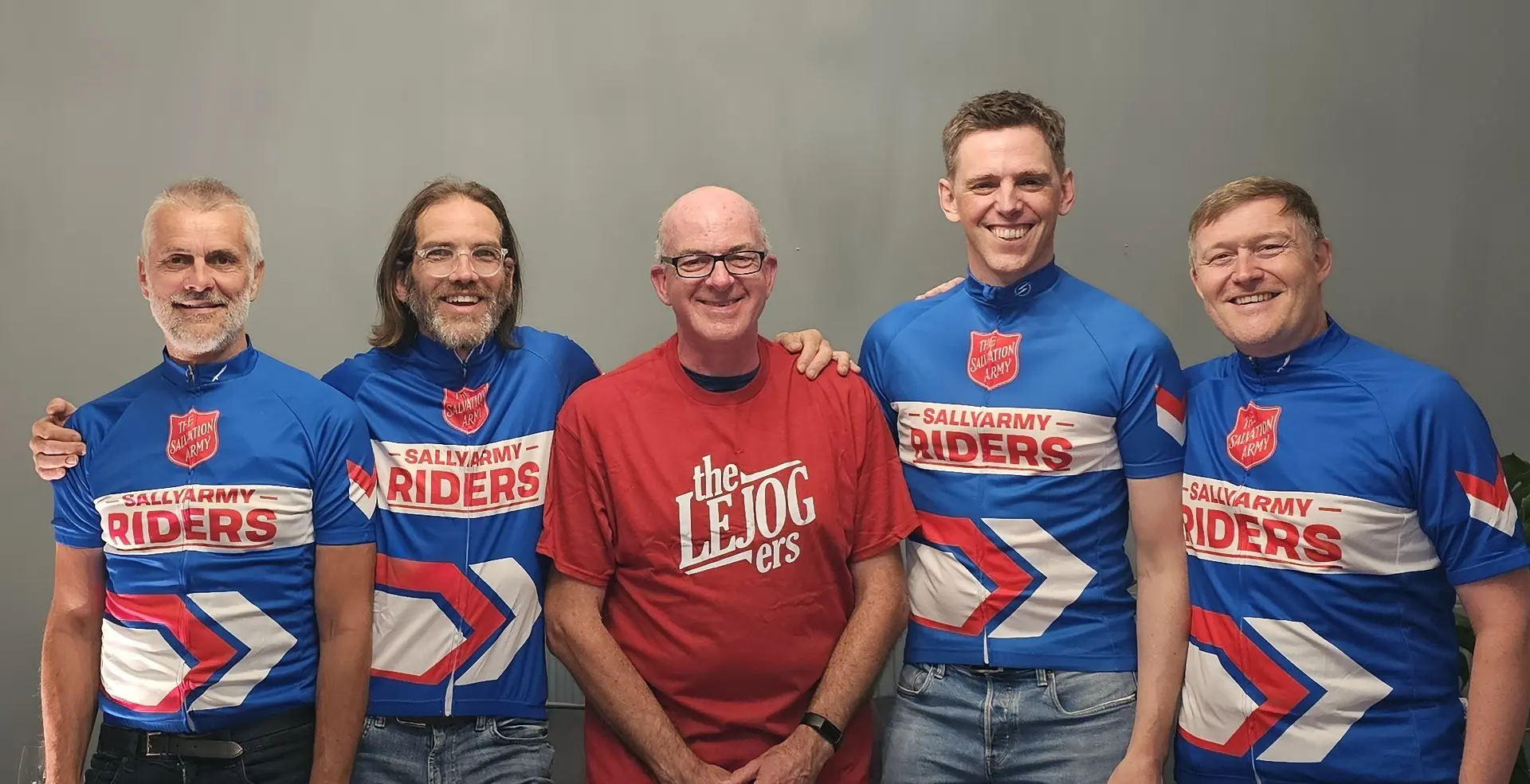 The 'LEJOGers. 5 men, 4 wearing Sally Army cycle jerseys and one wearing a red tshirt that says LEJOGers