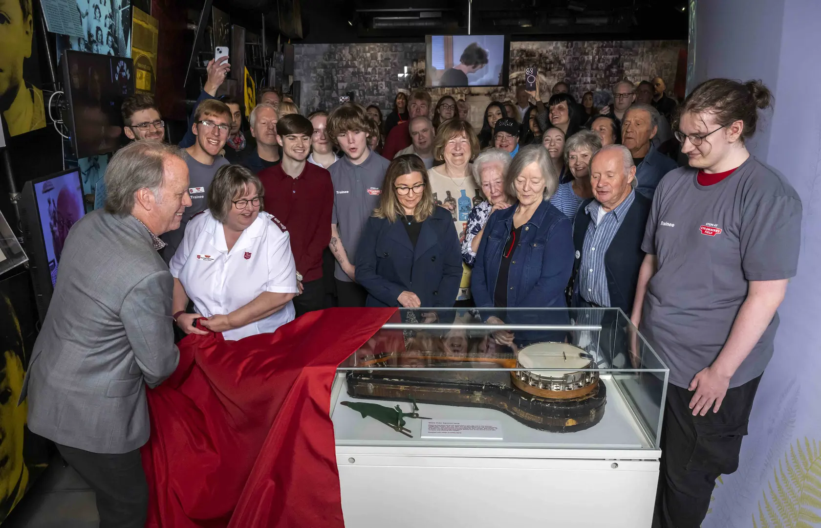 Crowd look on as a banjo is revealed in an exhibition