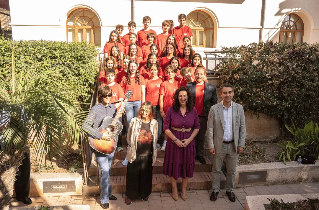 Julia Baird stands with a young choir, a guitarist and two dignitaries.
